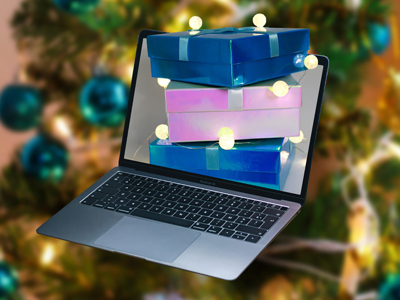 Geschenke vor einem Laptop und Weihnachtsbaum