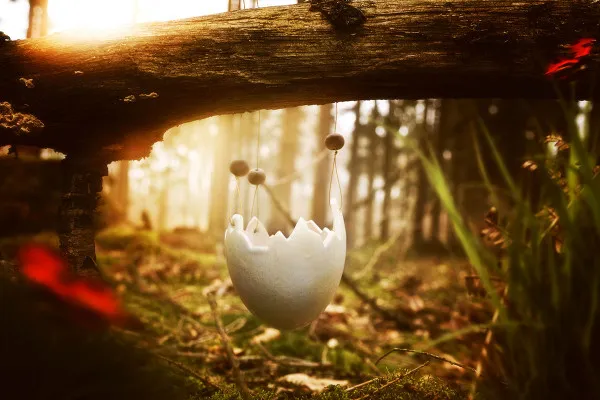 Bild eines Ostereis für zauberhafte Ostergrüße: aufgehängt an einem Baumstamm