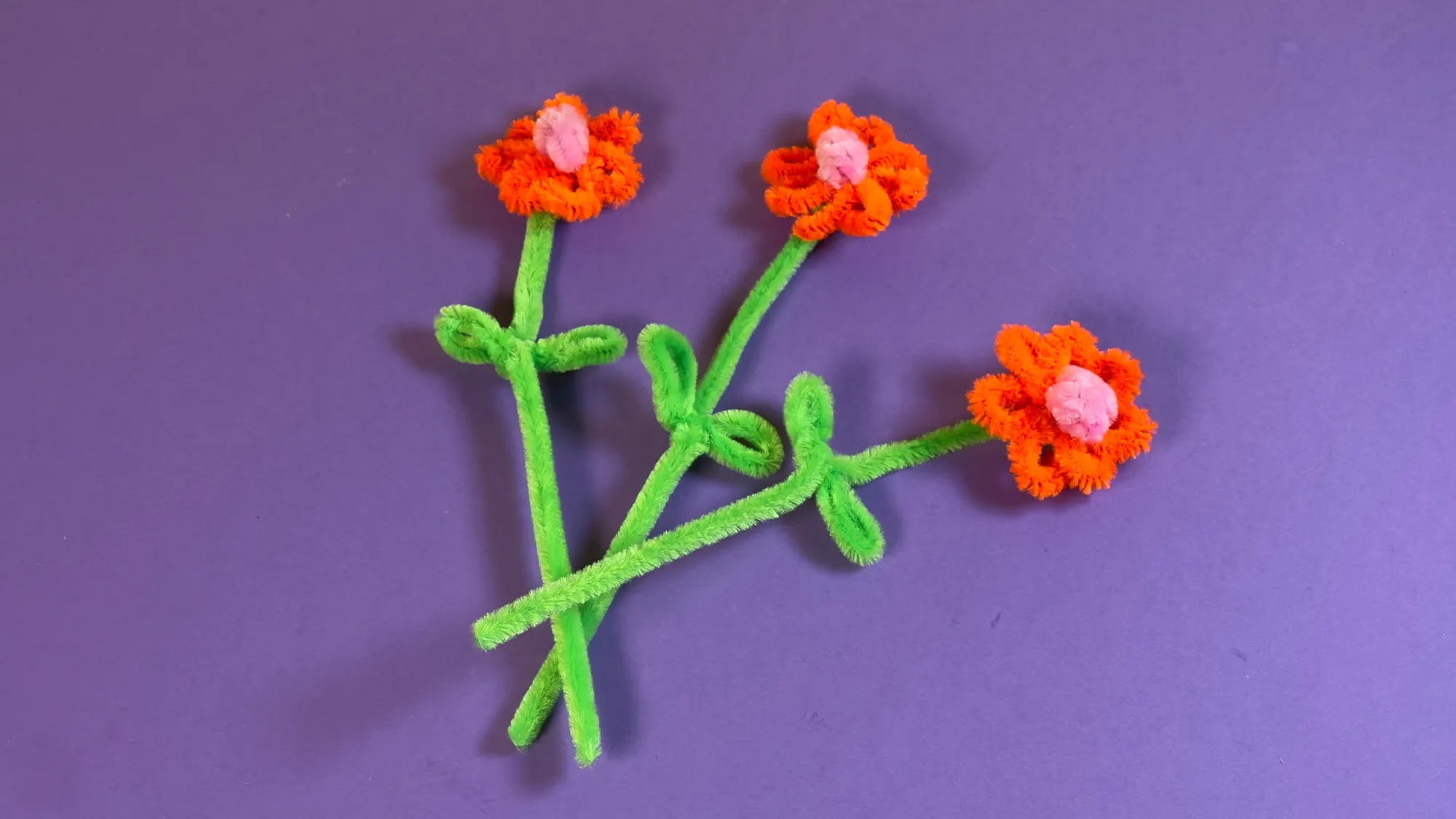 pfeifenputzer-blumen-basteln-schritt-3.jpg Pfeifenputzer-Blumen basteln Schritt 3: Grünen Stiel durch Blütenblätter stecken, festdrehen und kleine Blätter am Stiel formen