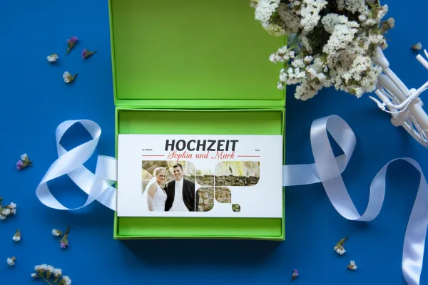 Mockup: Grüne Box mit Hochzeitseinladung, blauer Hintergrund