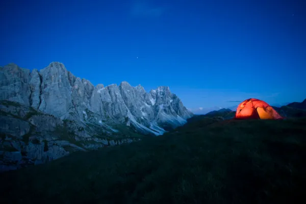 Bergfotografie: Gebirge, davor Zelt auf einer Wiese.