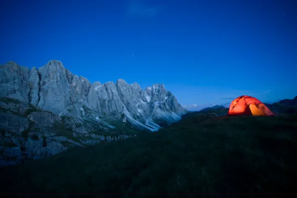 Fotografi gunung: pegunungan, di depan tenda di sebuah padang rumput.
