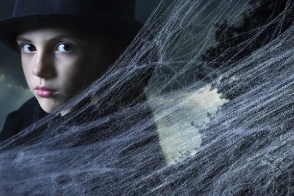 Kind mit schwarzem Hut, davor eingearbeitete Spinnennetze