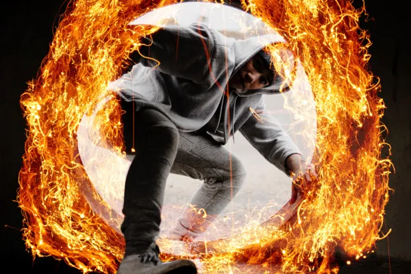 Junger Mann in cooler Pose, umgeben von einem Ring aus Feuer, der mit Feuer-Bildern kreiert wurde.