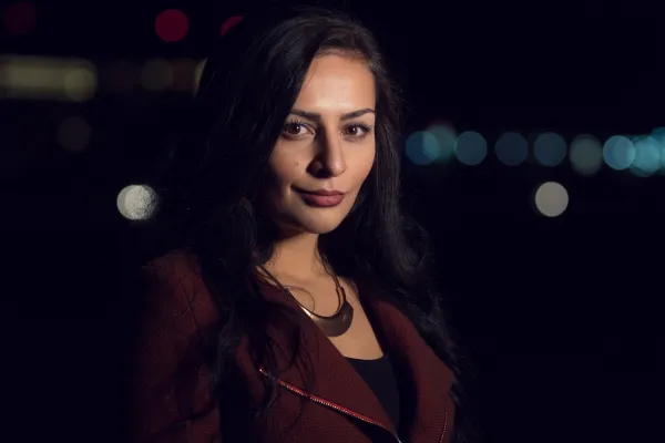 Potret seorang wanita di malam hari dengan bokeh di latar belakang.