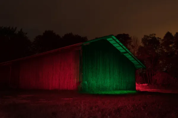 Membuat foto malam yang kreatif - dalam pelatihan, sebuah gudang yang terletak di dalam kegelapan disinari dengan cahaya gerak dan lampu LED berwarna.