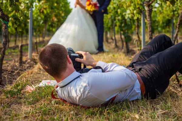 Hochzeitsfotografie: Hochzeitsfotograf auf einer Wiese liegend, um ein Brautpaar zu fotografieren