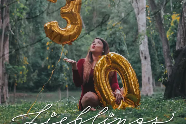 Foto einer Frau mit Luftballons und einem Handlettering zum Geburtstag