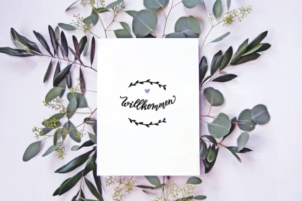 Grußkarte mit einem Handlettering, umgeben von Blumen